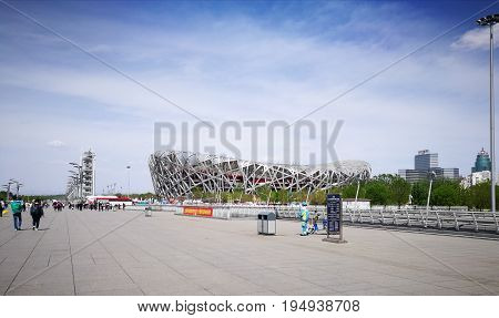 BEIJING, CHINA - APRIL 15, 2017: Beijing National Stadium or Bird's Nest Stadium. Tourists were visiting here. A woman in light-blue-uniform, with cleaning tools, was waiting to do her task.