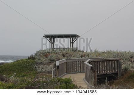Gazebo and footbridge surrounded by native plants at Asilomar State Beach in Pacific Grove, California on a cloudy day