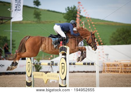 TURDA, CLUJ, ROMANIA - June 29, 2017: An unidentified competitor jumps with his horse at the Salina Equines Horse Trophy , June 29, 2017 in Turda, Cluj, Romania