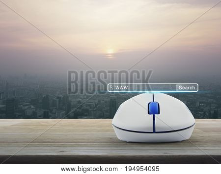 Search www button with wireless computer mouse on wooden table over modern city tower at sunset vintage style Searching system and internet concept