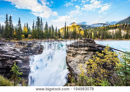 The full-water bubbling waterfall of Athabasca. Cold blue water at sunset. Clear autumn evening in Jasper National Park. The concept of extreme and ecological tourism