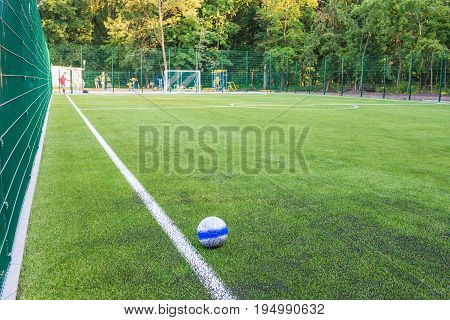 The ball lies on the green grass of the new football field. You can use this picture to popularize sports and healthy lifestyles.