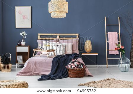 Wooden breakfast tray with two glasses and bottle standing on king-size bed