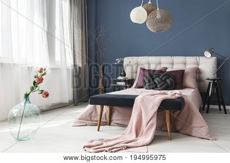 Pink fresh roses in big glass vase standing in elegant cozy bedroom