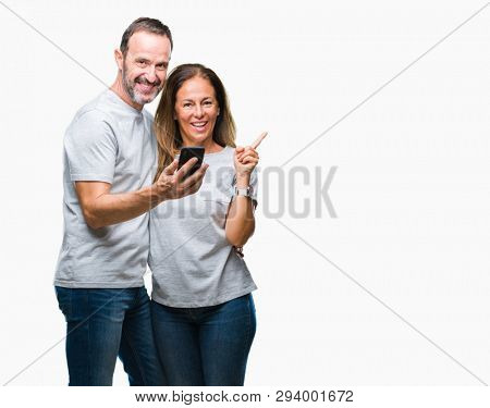 Middle age hispanic couple texting message on smartphone ver isolated background very happy pointing with hand and finger to the side