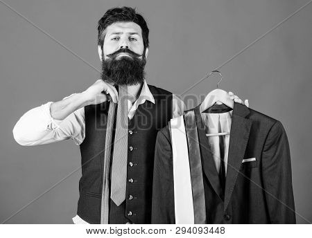 How About This Tie. Brutal Hipster Holding Colorful Tie Collection And Suit Jacket. Bearded Man Matc
