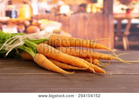 Lot Of Whole Fresh Orange Carrot Bunch With Greens Tied By Jute In A Rustic Kitchen