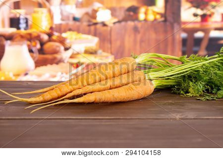 Group Of Five Whole Fresh Orange Carrot Bunch With Greens In A Rustic Kitchen