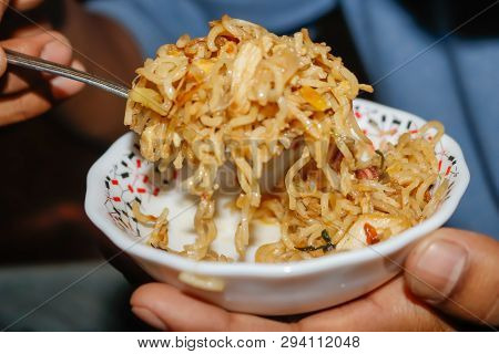 Someone Eating Noddles In A White Plate With Spoon.