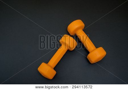 Two Orange Dumbbells Isolated On Black Background