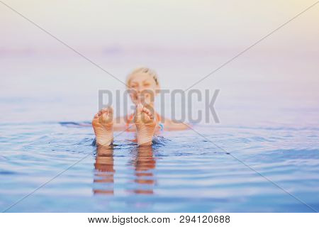Asian Young Adult Woman Lying And Relaxing In Infinity Swim Pool At Spa Resort. Summer Holidays Trav
