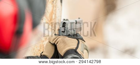 Close-up Detail View Of Hands In Gloves Holding Gun