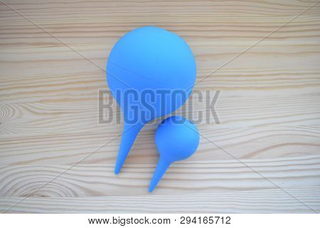 Two Blue Rubber Syringe On A Wooden Board