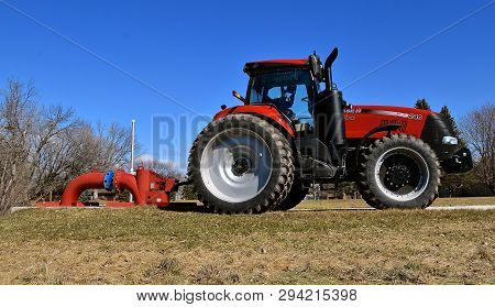 Moorhead, Minnesota, March 7, 2019:  The Huge Red 240 Magnum Tractor Pumping Water At A Lift Station