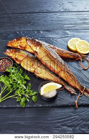 Hot Smoked Whole Herrings With Lemon Slices, Parsley And Peppercorns On A Black Slate Tray  On A Woo
