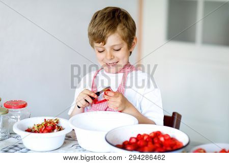Little Blond Kid Boy Helping And Making Strawberry Jam In Summer. Funny Child Cleaning Berries And P