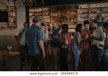 Friends Talking And Drinking Together In A Bar At Night
