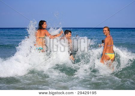 Gruppo di tre amici - uomo e donna - sulla spiaggia avendo un sacco di divertimento in vacanza in Grecia