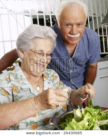 Feliz pareja senior, preparación de ensalada de verduras en la cocina. Abuelos en la cocina preparando vege