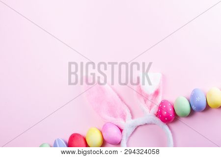 Easter Rabbit Flaffy Ears And Colored Easter Eggs Row On Pink Background With Copy Space