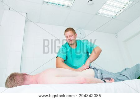 Patient Receiving Massage From Therapist. A Chiropractor Does Deep Tissue Massage On Man's Loins In 