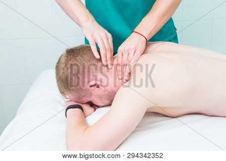 Physiotherapist Massaging Male Patient With Injured Neck Muscle. Sports Injury Treatment, Reabilitat