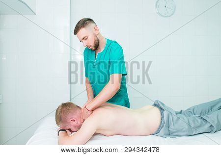 Physiotherapist Massaging Male Patient With Injured Neck Muscle. Sports Injury Treatment, Reabilitat