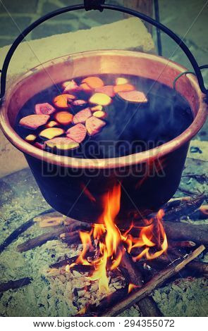 Hot Mulled Wine On The Cauldron Over The Bonfire In Winter  With Old Toned Effect