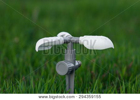 Gardening Concept. Watering Concept. Rotating Sprinkler On Fresh And Green Grass Background. Copy Sp