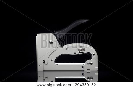 Front View On Manual Hand Tool Grey Staple Gun Isolated On Black Background And Mirror Surface.