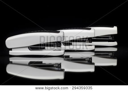 Front View On White Office Stapler Isolated On Black Background On Mirror Surface.