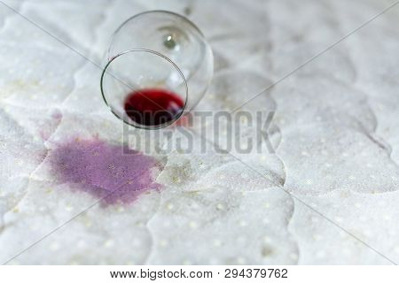 Wine Glass Spilled On Bed. Dropped Wineglass On White Bed Sheet. Pink Wet Stain. Unlucky, Unfortunat