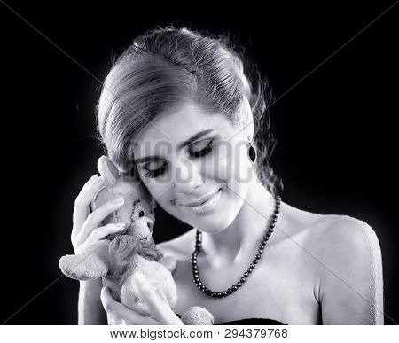 Tailoring soft toys with their own hands. Young lady cuddles newly made stuffed bear toy. Black and white old retro photo.