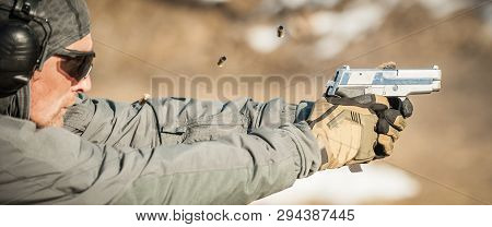 Shooter Holding Gun In Hand And Shooting. Close-up Detail View