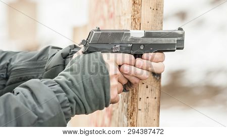 Close-up Detail View Of Shooter Hands Holding Gun And Shooting