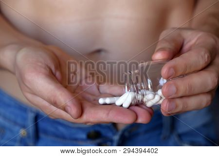 Man Taking Pills, Bottle With Capsules In Male Hands Close Up. Muscular Guy In Unzipped Jeans With N