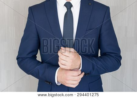 Torso Of Anonymous Businessman Wearing Beautiful Fashionable Classic Navy Blue Suit Against Grey Bac