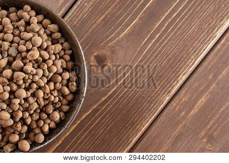 Lot Of Whole Brown Clay Pebbles (leca) On Grey Ceramic Plate Flatlay On Brown Wood