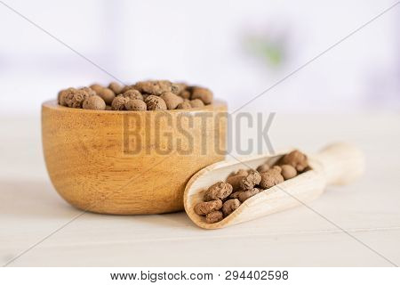 Lot Of Whole Brown Clay Pebbles (leca) With Wooden Bowl And Wooden Scoop With Flowers In A White Kit