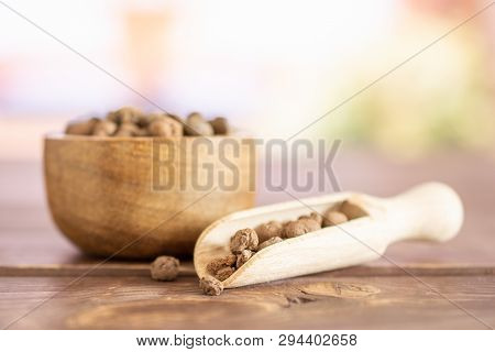 Lot Of Whole Brown Clay Pebbles (leca) With Wooden Bowl And Wooden Scoop With Books Near The Window 