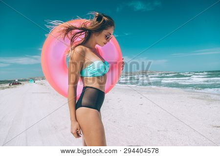 Girl relaxing on pink lilo on the beach. Playing with inflatable ring. Summer holiday idyllic on a tropical island.