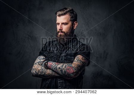 Portrait Of A Tattooed Man With Beard And Hairstyle Posing With His Arms Crossed. Studio Photo Again