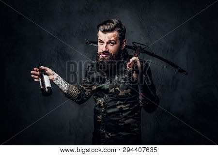 Stylish Bearded Hipster Man In Military Shirt Holding A Craft Beer And A Medieval Crossbow. Studio P