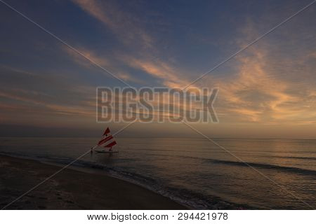 Captiva Island, Florida 08-05-2015 Small Sailboat In Partial Silhouette Against The Setting Sun In T
