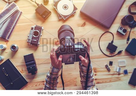 Top View Of Female Photographer Holding Digital Camera Above The Desk In Her Photo Studio