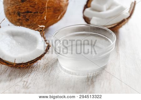 Whole Coconut Cut Into Chunks And Chips And Milk On A Light White Wooden Background. Top View