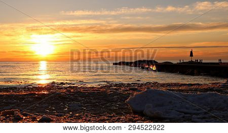 Magnificent Spring Sunset Reflecting On  Water Ice And Snow While People Enjoy Fishing Or An Evening