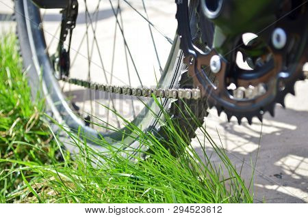 New Chain And New Transmission On An Old Grey Bike That Stands On The Grass, A Bottom View, With Sha