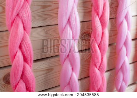 Kanekalon Hangs On A Wooden Background Of Pink, Fuchsia Red In Different Shades Similar