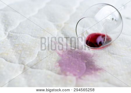 Wine Glass Spilled On Bed. Dropped Wineglass On White Bed Sheet. Pink Wet Stain. Unlucky, Unfortunat
